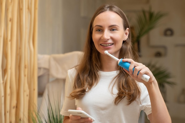 Woman brushing teeth and reading message on phone from bathroom girl with smartphone using