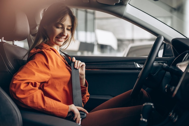 Woman buckles up the safety belt in a car