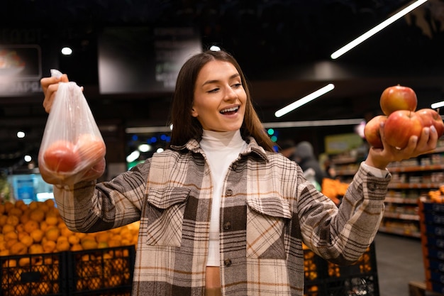 Woman buying apples in a supermarket against plastic bags