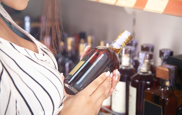 Woman buying cognac at supermarket.