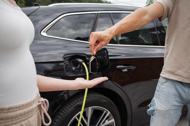 Woman buying electric car man hand is giving her the key