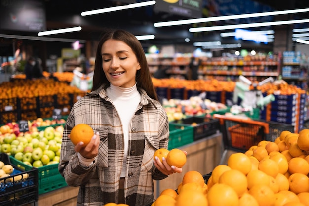 Woman buying fresh oranges at the grocery supermarket