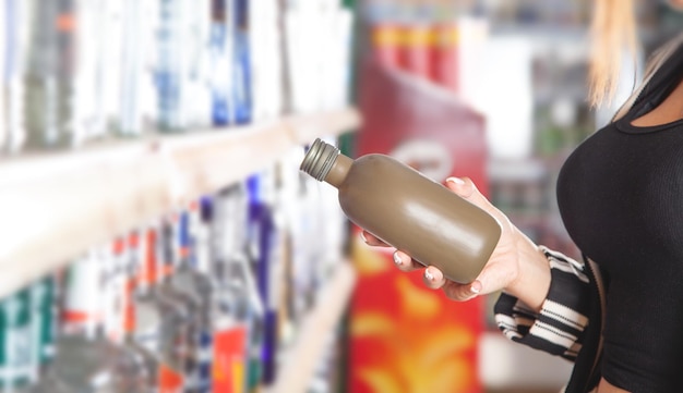 Woman buying vodka at supermarket