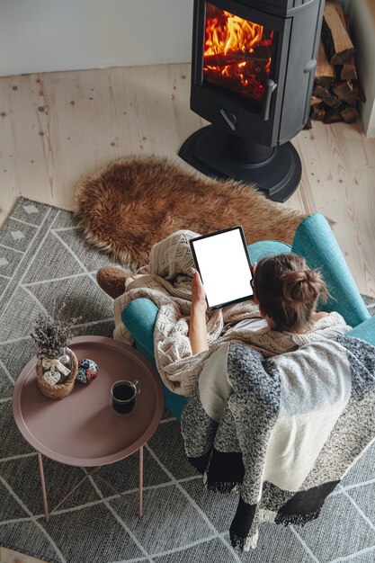 Woman by the fireplace, sitting in a cozy armchair, with a warm