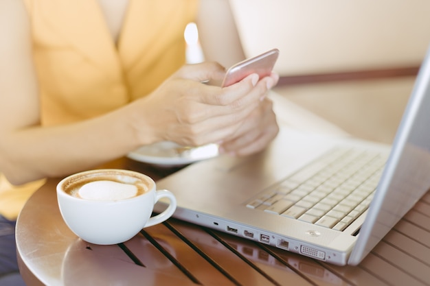 Woman at cafe drinking coffee and use mobile phone for business.