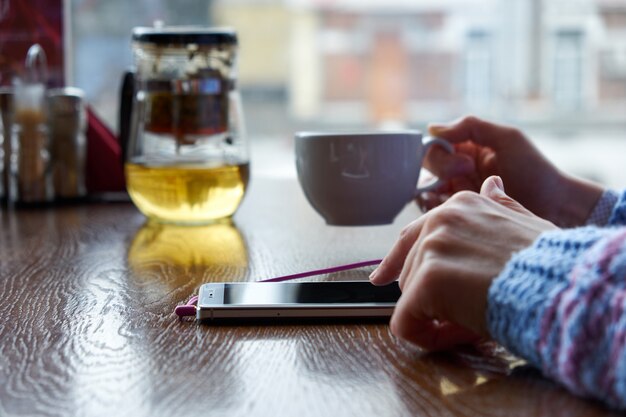 Woman in cafe holding phone. For Graphic display montage.