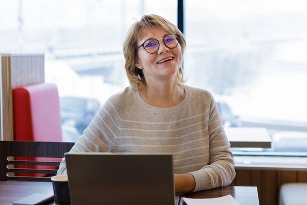 Woman in cafe and office working with laptop