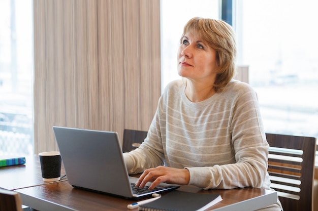 A woman in a cafe working on a laptop. The concept of business and remote work.