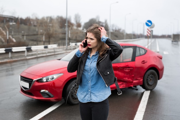 Woman calls to a service standing by a red car