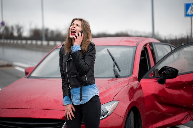 Woman calls to a service standing by a red car