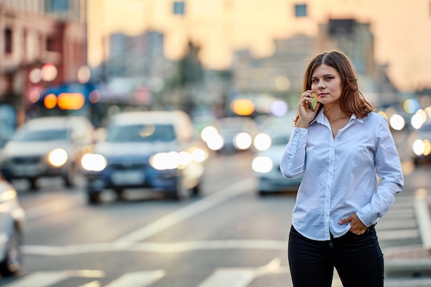 Woman calls for taxi on traffic street in evening