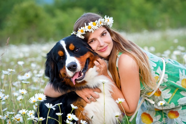 Woman in camomile wreath with Bernese Mountain Dog. Girl with dog