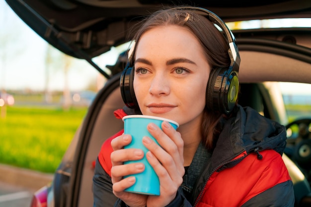 Woman in car autumn concept Smiling beautiful girl listening to music