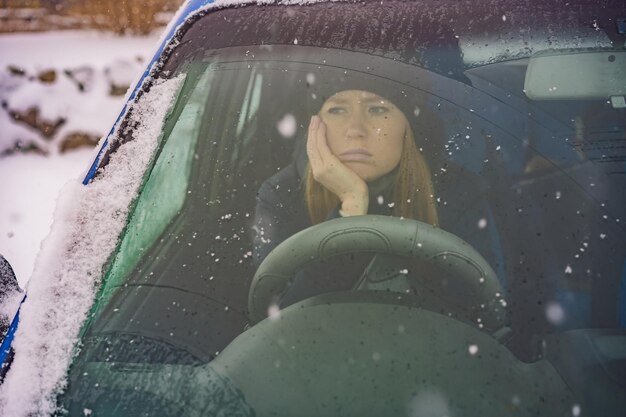 Woman in a car during a snowfall problems on the road