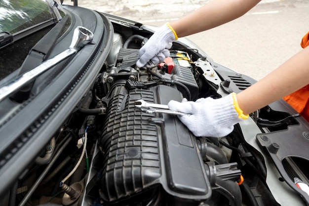 Woman car technician in uniform checking the car engine