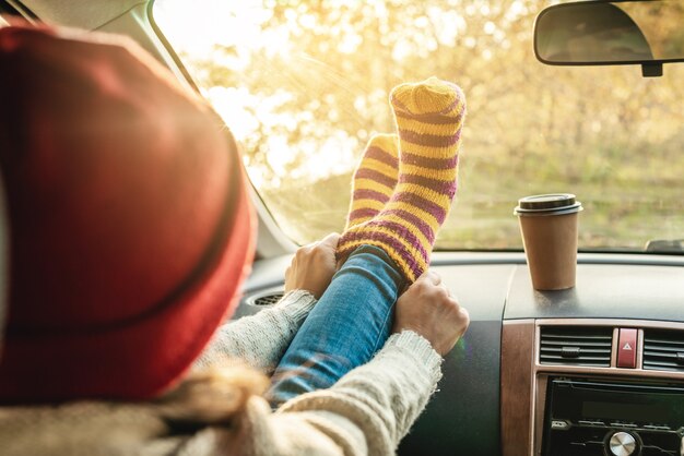 Woman in a car in warm woolen yellow socks on the car dashboard