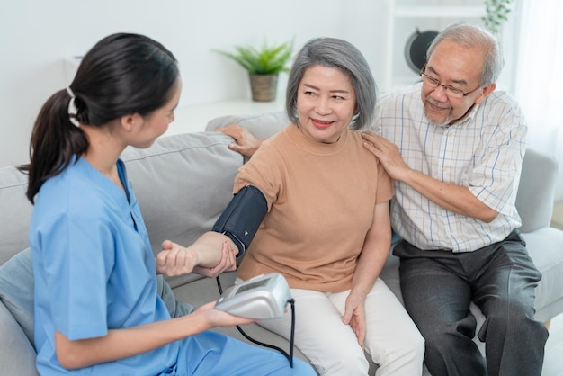 Woman caregiver using pressure gauge measure blood pressure elderly woman patient during home visit