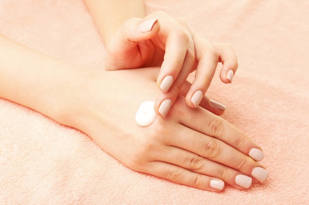 Woman caring hands with cream on fabric background