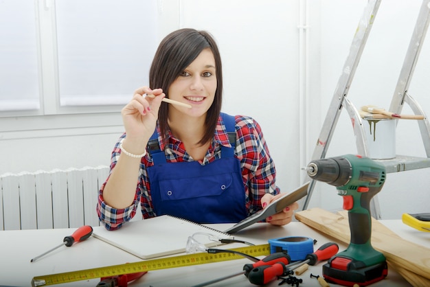 Woman carpenter sitting at desk in her workshop 