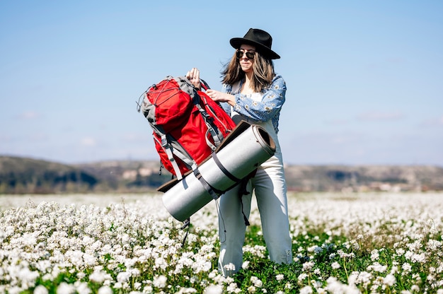 Woman carrying her red backpack in the field