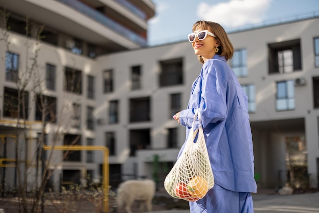 Woman carrying meshbag with fresh groceries while walking home