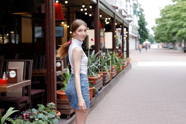 A woman in casual clothes smiles and walks down the street