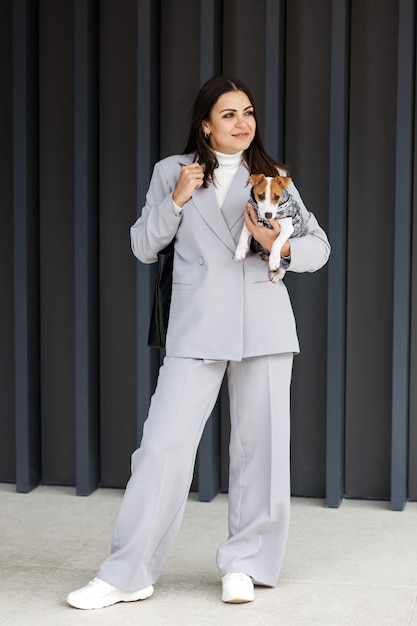 Woman in casual jacket standing with her fluffy trained purebred Jack Russell Terrier dog