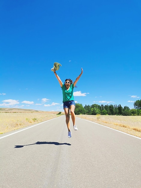 Woman celebrating running jumping jumping and playing on a lonely road