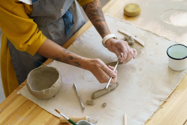 Woman ceramist make pottery cup in studio creative girl pottery master with tattoo shaping pot mug