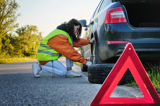 Woman changes the damaged wheel of the car