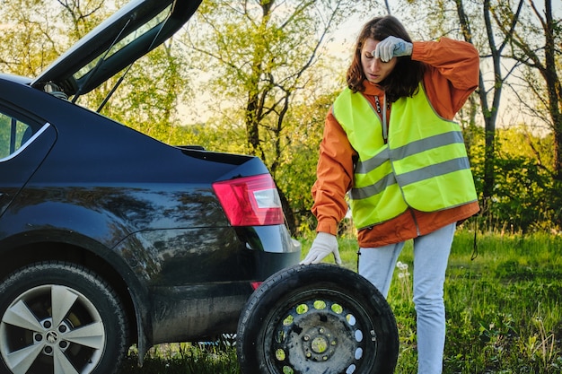 Woman changes the damaged wheel of the car