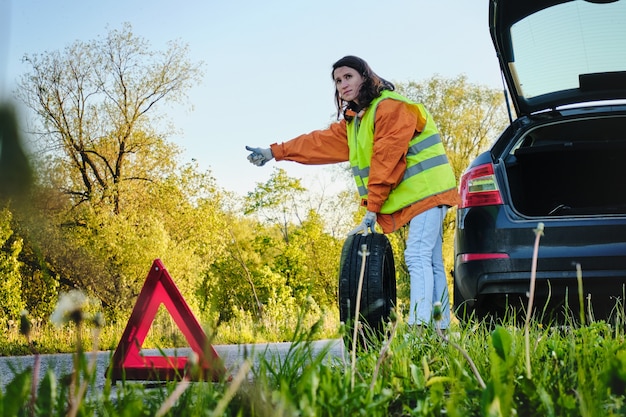 Woman changes the damaged wheel of the car