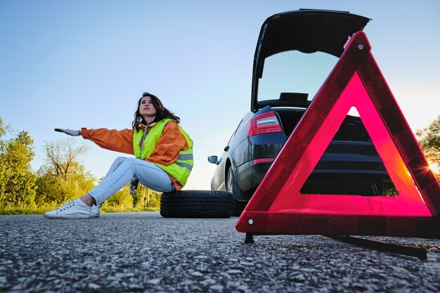 Woman changes the damaged wheel of the car