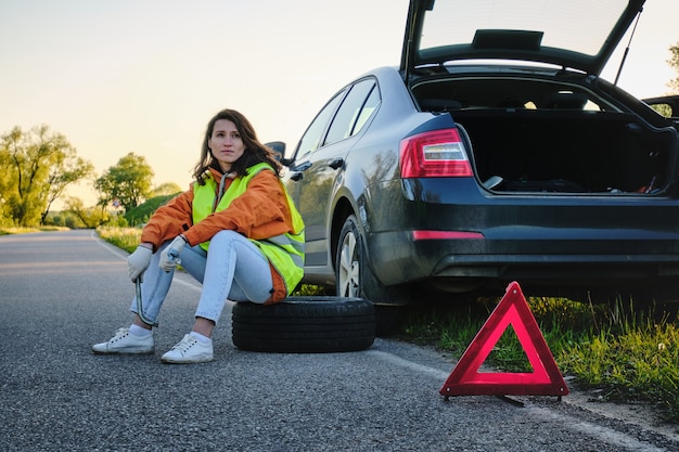 Woman changes the damaged wheel of the car