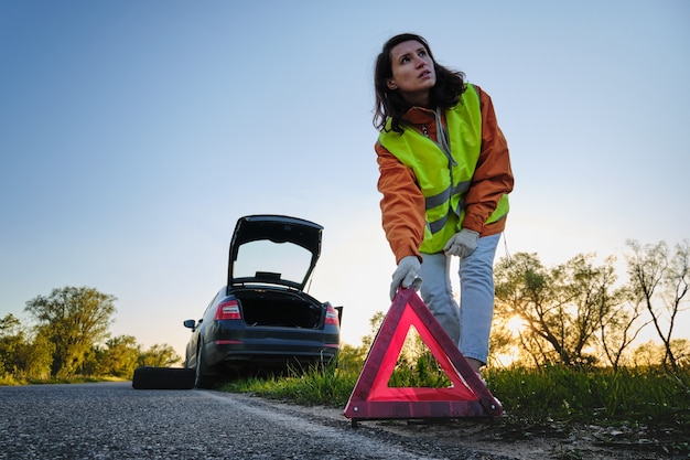 Woman changes the damaged wheel of the car