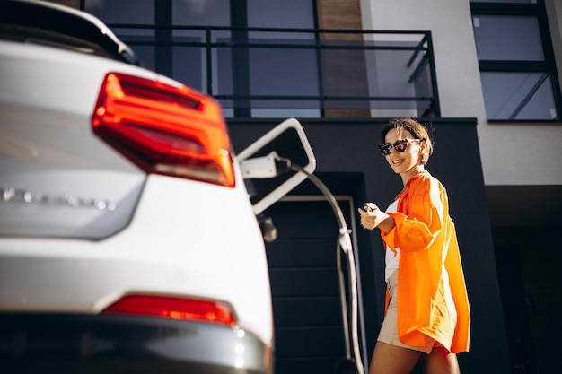 Woman charging electric car by her house