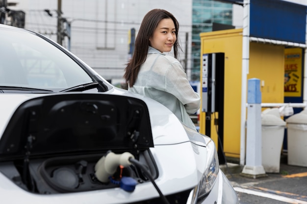 Woman charging her electric car at the station