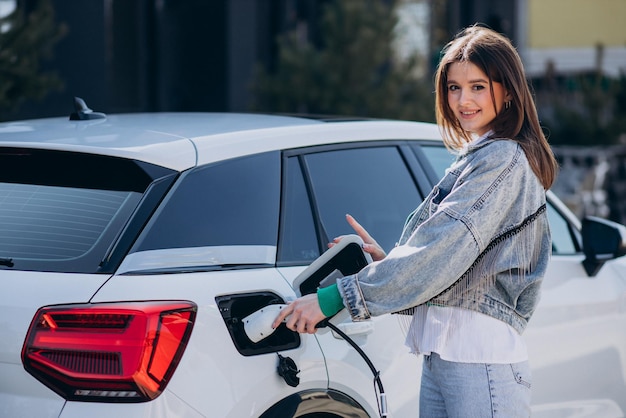 Woman charging her electric car with charging pistol