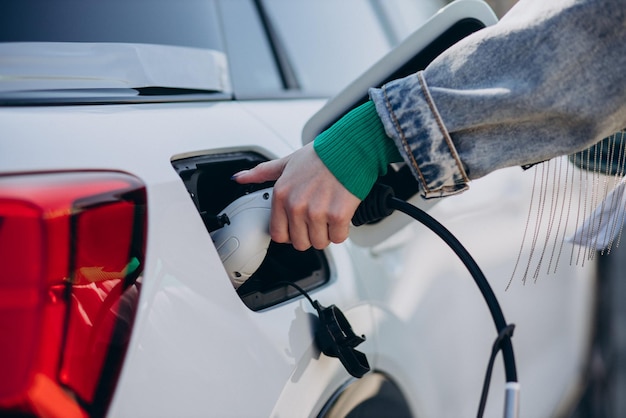 Woman charging her electric car with charging pistol