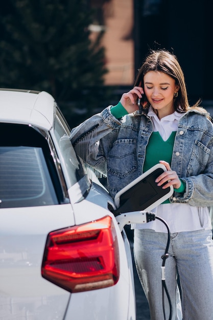 Woman charging her electric car with charging pistol