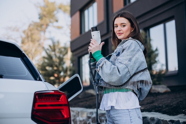 Woman charging her electric car with charging pistol