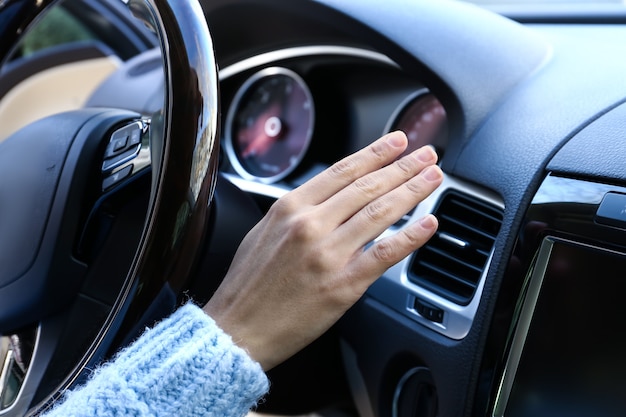 Woman checking operation of air conditioner in car