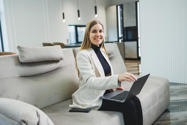 Woman cheerful charming person sitting behind a netbook watching having a good mood working at home indoors Remote freelance work