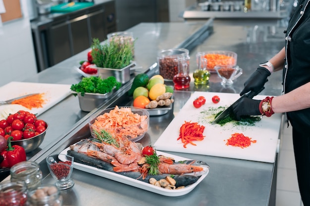 A Woman Chef cuts vegetables in the kitchen in a restaurant