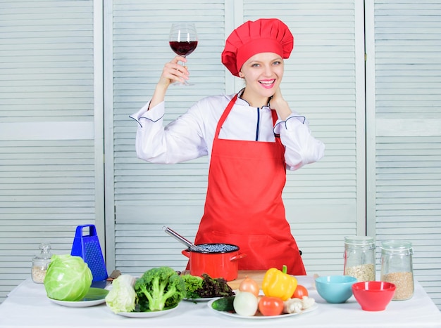 Woman chef hold glass of wine. Which wine to serve with dinner. Exquisite dinner concept. Wine degustation. How to match wine and food like expert. Girl wear hat and apron enjoy aroma of drink.