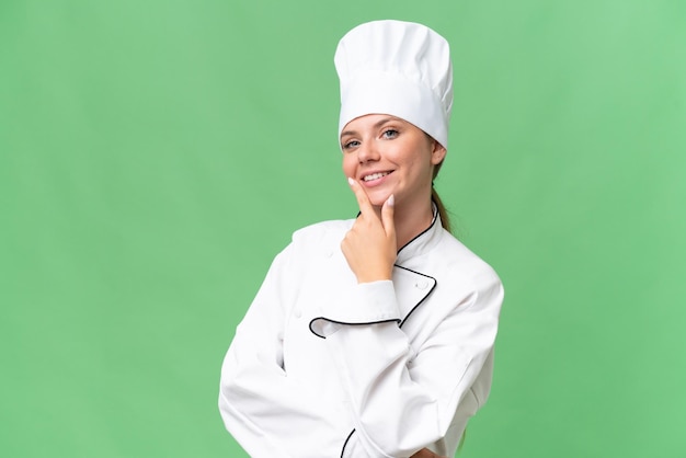 A woman in a chef uniform stands in front of a green screen