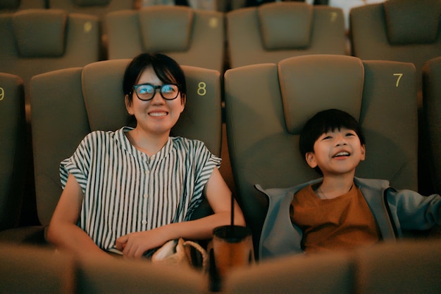 a woman and a child are sitting in a movie theater