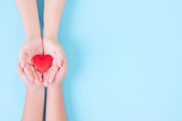 Woman and child holding heart on light blue