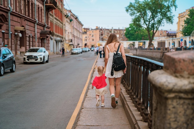 a woman and a child walking down a sidewalk with a woman holding a bag