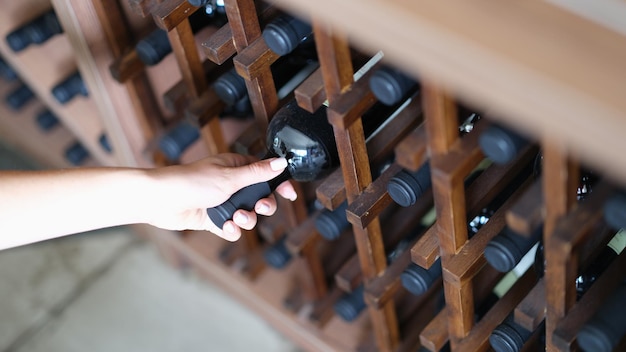 Woman chooses bottle of wine in cellar closeup